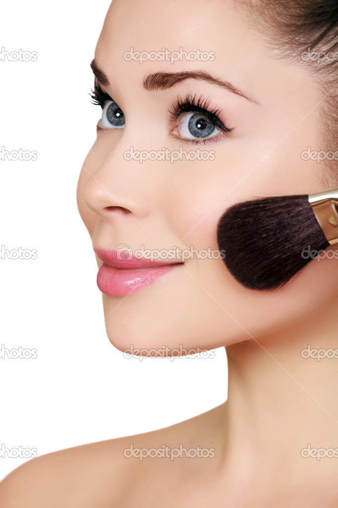Beautiful woman doing make-up on face with cosmetic brush