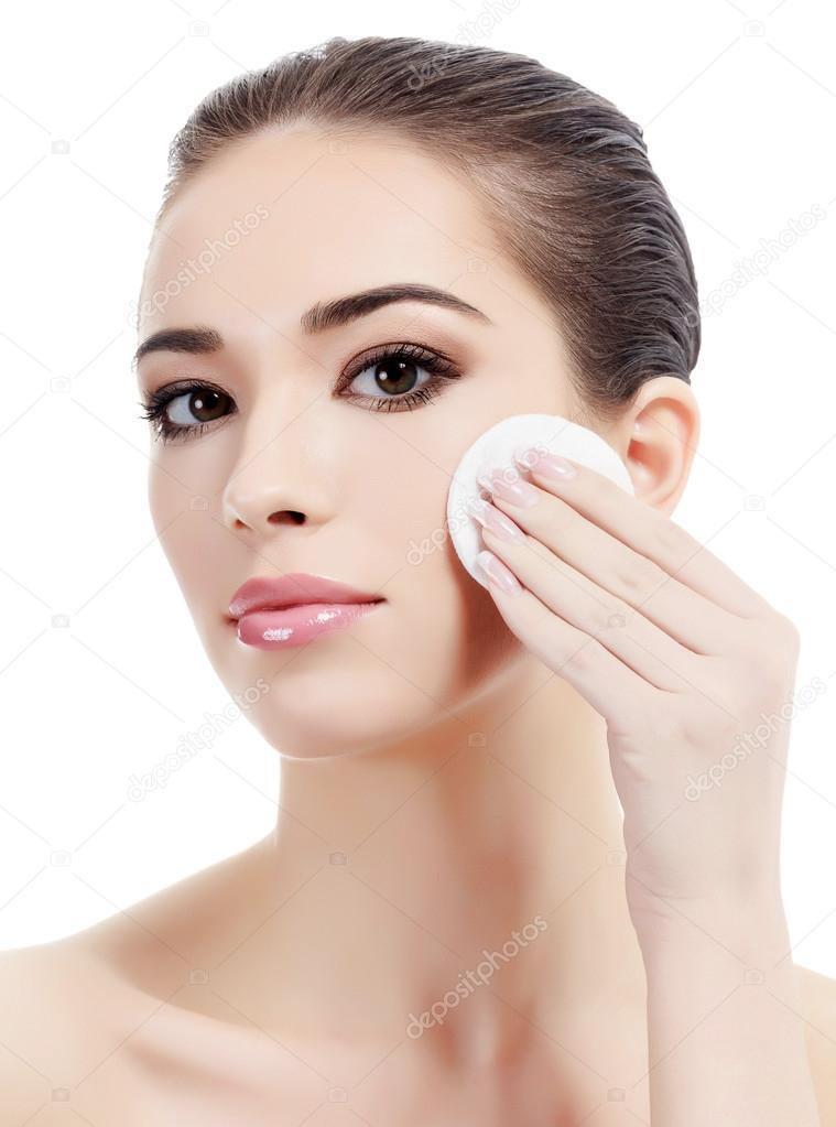 Beautiful woman using a cotton pad to remove her makeup