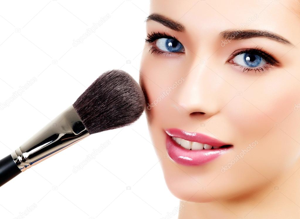 Pretty woman with a cosmetic brush, white background