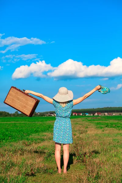 Vrouw in zomerjurk met een koffer — Stockfoto