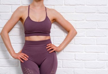 İnce kadın beyaz tuğla duvara karşı poz veriyor.