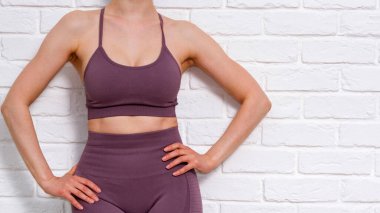 İnce kadın beyaz tuğla duvara karşı poz veriyor.