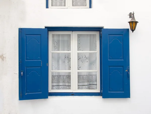 Oude venster met blauwe luiken en witte gordijn. achtergrond. — Stockfoto