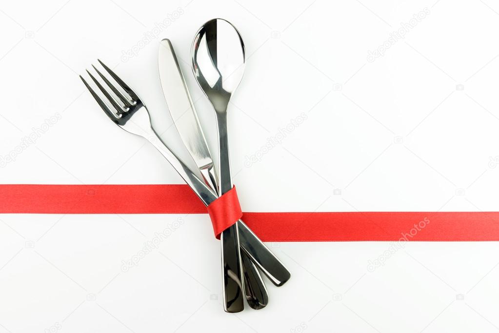 Fork, knife and spoon tied up with red ribbon