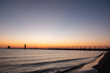 Michigan Gölü 'ndeki Grand Haven deniz fenerinde ve rıhtımında gün batımı, Michigan, ABD