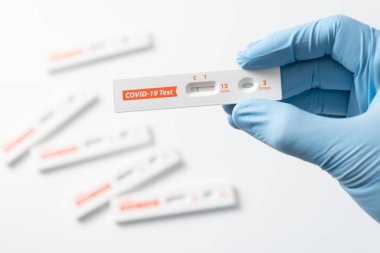 Hand with glove is showing negative results on test strip for rapid antigen home Covid-19 test kit at home.
