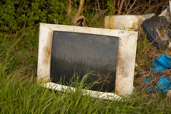 Выброшенный старый телевизор на поле — стоковое фото