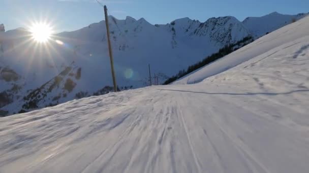 Esquiar por una pendiente la luz del sol que brilla desde la puesta del sol — Vídeos de Stock
