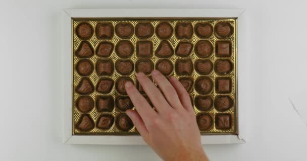 Tomando trozos de caramelo de la caja de bombones, disuadiendo a mano la tentación — Vídeos de Stock