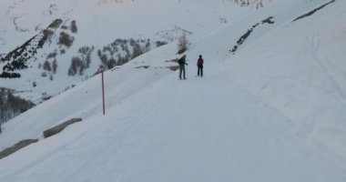 Kar ayakkabısı yürüyüşçülerinin yanından geçen bir yamaçtan kayak yapmak.