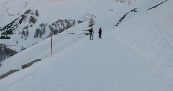 Skifahren am Hang vorbei an Schneeschuhwanderern — Stockvideo