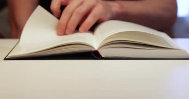 Bir odada bir masada kitap, adam okuyor.