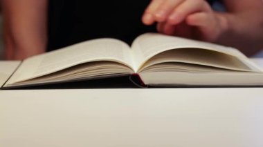 Bir odada bir masada kitap, adam okuyor.