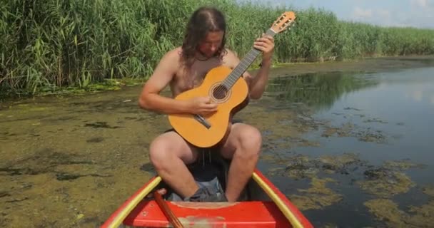 Tocando guitarra em uma canoa no verão — Vídeo de Stock