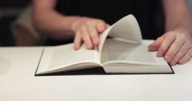 Bir odada bir masada kitap, adam okuyor.