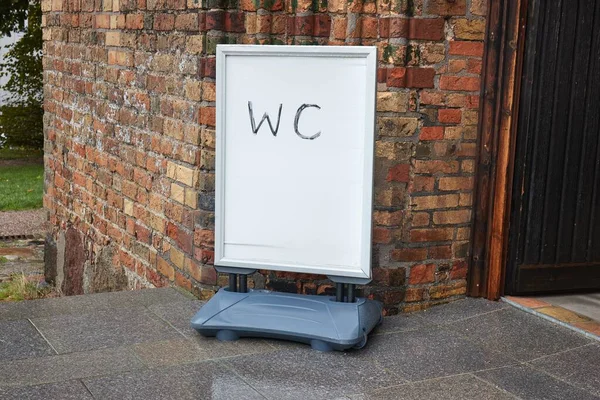 Placa do sinal do WC na entrada velha do edifício do tijolo — Fotografia de Stock