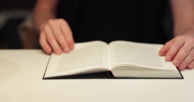 Bir odada bir masada kitap, adam okuyor.