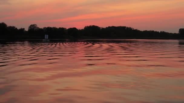 Zonsondergang boven een rustig meer, reflectie van de watergolf — Stockvideo
