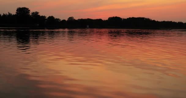 Ηλιοβασίλεμα πάνω από μια ήρεμη λίμνη, αντανάκλαση κύματος νερού — Αρχείο Βίντεο