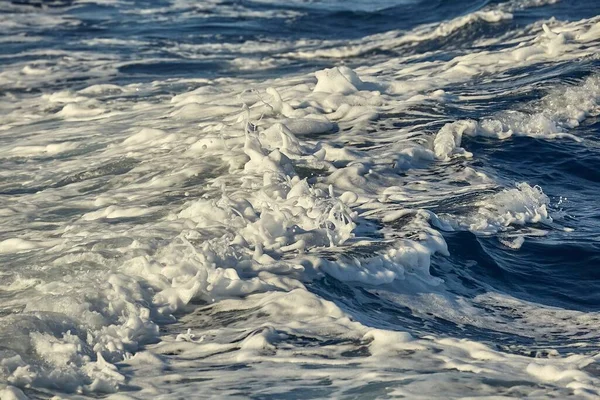 Vagues avec éclaboussures de mousse dans l'eau de mer — Photo