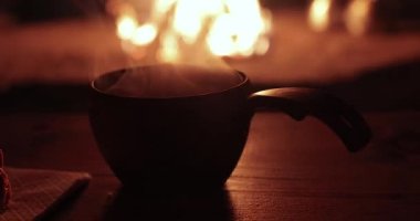 Finnish Lapland 'dan Tami Kuksa, şöminenin yanında yükselen sıcak çay buharı rahat ahşap bir kulübede oturuyor, geleneksel yaşam tarzı.