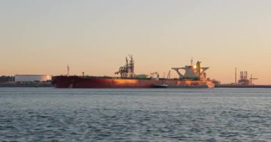 Büyük ham petrol tankeri Rotterdam 'daki Maasvlakte Petrol Terminali' ne demirlemiş. Sabah güneş doğuyor.