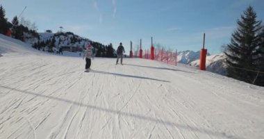 Alplerde snowboard ve kayak, bir grup arkadaş neşeyle yamaçtan aşağı iniyor.