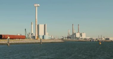Rotterdam Limanı 'ndaki Maasvlakte' deki elektrik santralleri ve diğer endüstriyel yapılar, ön planda yapım aşamasında olan rüzgar türbini