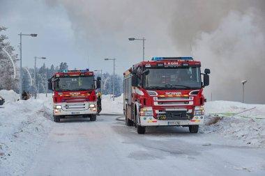 Saariselka, Finlandiya - 2022 civarı: Fin Laponya 'daki alışveriş merkezi Kuukkeli' de yanan itfaiye araçları. İtfaiyeciler yayılan alevleri durdurmaya çalışıyor.