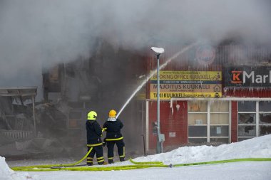 Saariselka, Finlandiya - 2022 civarı: Finlandiya 'daki alışveriş merkezi Kuukkeli' nin yakılması. İtfaiyeciler alevleri durdurmaya çalışıyor.