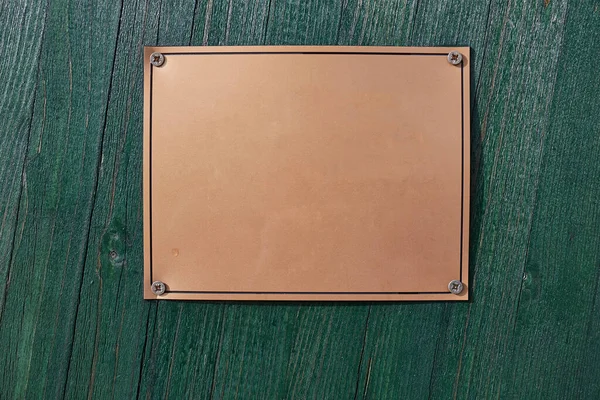 Blank sign plaque on a wooden gate for street name, house number or memorial plate