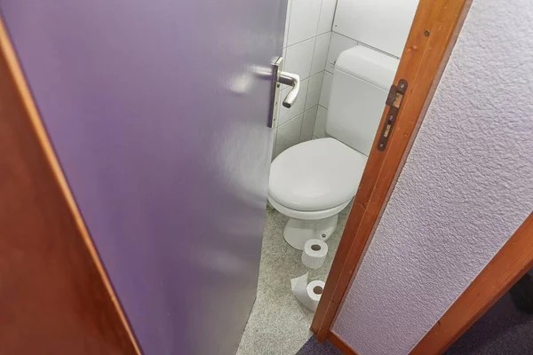 地板上有卫生纸卷的厕所 门半开 — 图库照片