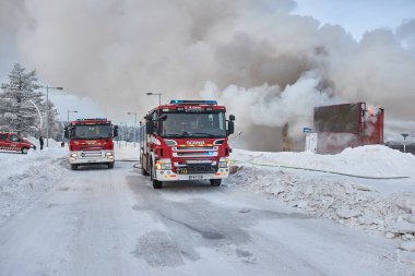Saariselka, Finlandiya - 2022 civarı: Fin Laponya 'daki alışveriş merkezi Kuukkeli' de yanan itfaiye araçları. İtfaiyeciler yayılan alevleri durdurmaya çalışıyor.
