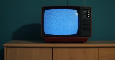 Ekranın loş bir odasında sinyal sesi olmayan eski bir televizyon. Siyah beyaz televizyon.