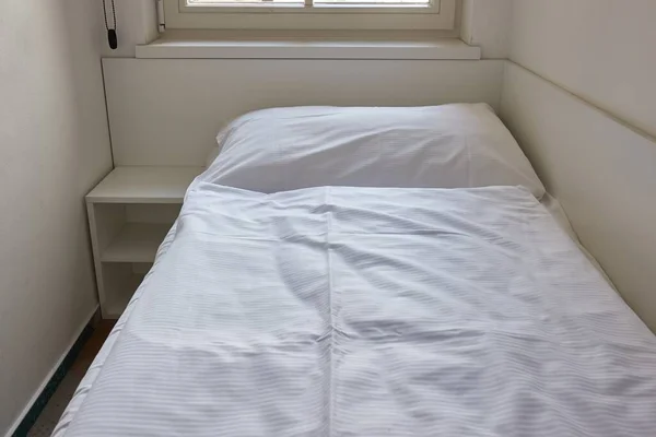 Bed made with sheets in a simple hostel dormitory