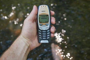 Prag, Çek Cumhuriyeti - 2022 dolaylarında Nokia 6310i cep telefonu taze bir orman deresinin su yüzeyinde kullanılmıştır..