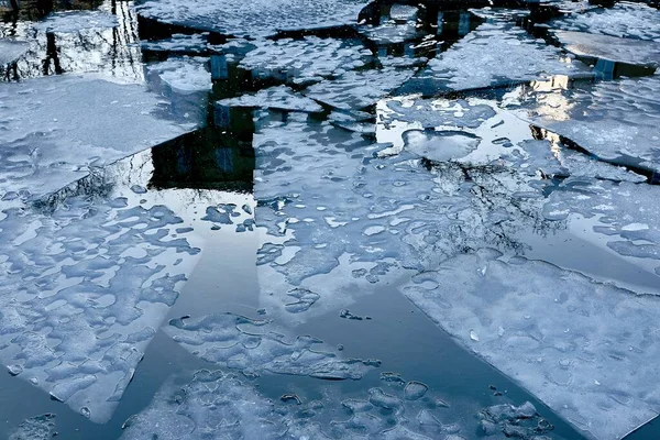 Ice sheets on a frozen water body with town building reflections in Helsinki