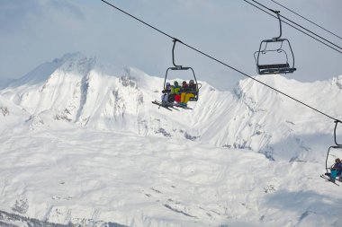 LA PLAGNE, FRANCE - CIRCA 2016: Ski lifts and skiers in the bright sunlight on a slope with good view over the mountains. Part of Paradiski ski resort, one of the biggest in Europe clipart