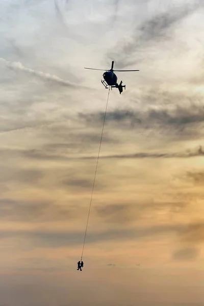 Helikopter Ratowniczy Latający Ludźmi Wiszącymi Linie — Zdjęcie stockowe