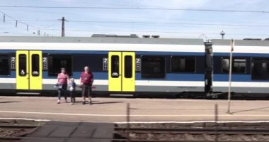 Budapeşte, Macaristan - 2021 dolaylarında: Tren istasyonundan ayrılmak, tren penceresi manzarası, bir banliyö treninin önündeki perondaki yolcular