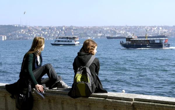 两个女孩正坐在伊斯坦布尔博斯普鲁斯海峡 图库图片