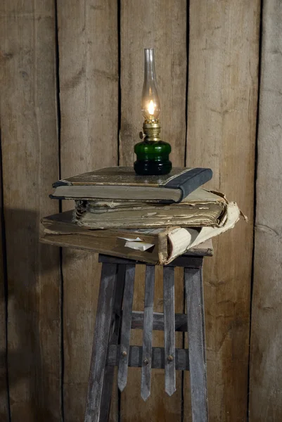 Lâmpada de querosene e pilha de livros antigos — Fotografia de Stock