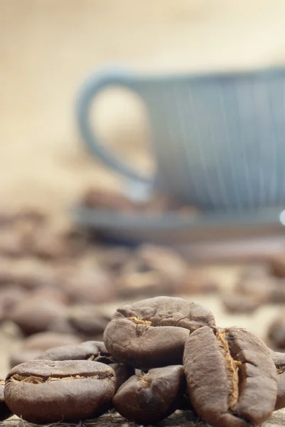 Four cocoa beans close-up on burlap, and in the background a cup — Stock Photo, Image