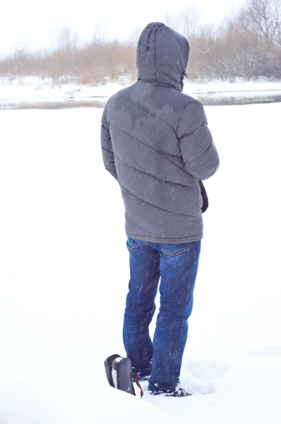 Человек взял термос с горячим чаем в поход, когда идет снег — стоковое фото