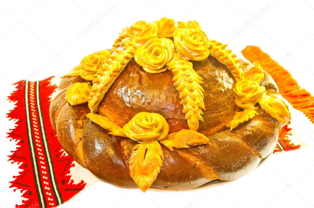 Bread decorated with flowers and wheat ears. Isolated on white b
