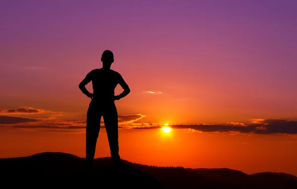 Silhouette eines jungen Mannes in den Bergen bei Sonnenuntergang — Stockfoto