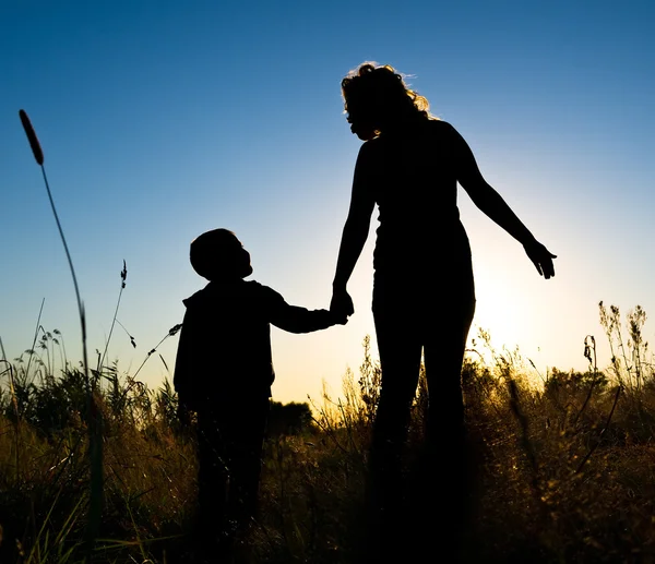 Silhouette of a young boy and his mother in the field in summer — Stock Photo, Image