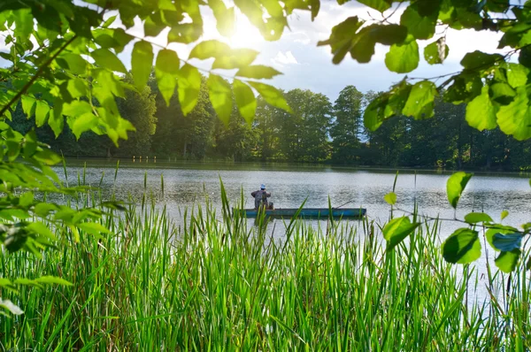 Заядлый рыбак в лодке на озере. Летняя ловля Стоковое Изображение