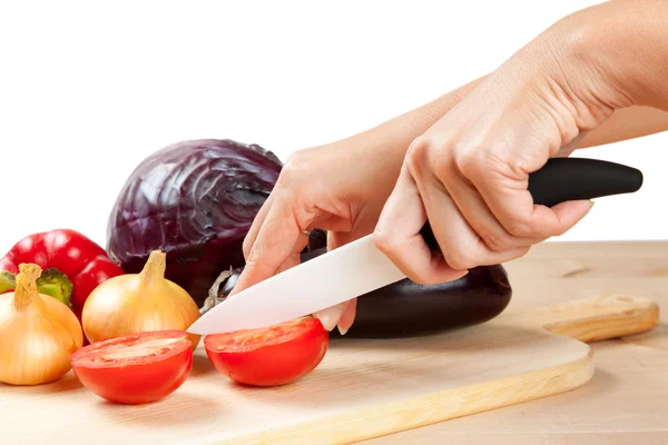 Керамический нож с овощами на доске — стоковое фото