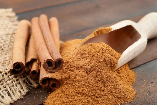 Paus de canela e pó de canela em colher de madeira — Fotografia de Stock